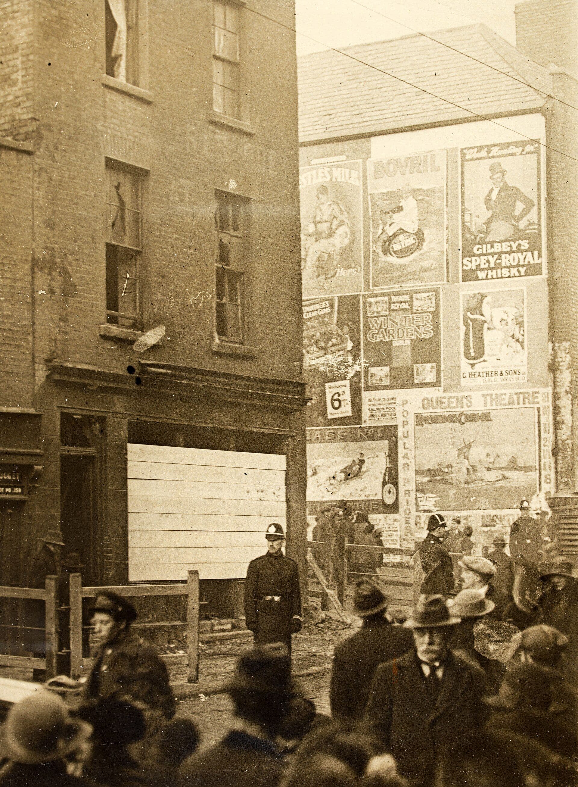 Dublin street, about 1923: a gable wall covered in advertising posters above a crowd and a policeman.